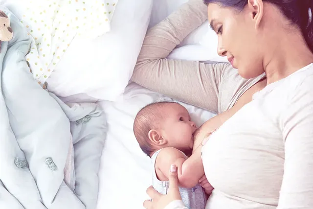 Mutter stillt ihr kleines Baby im Bett