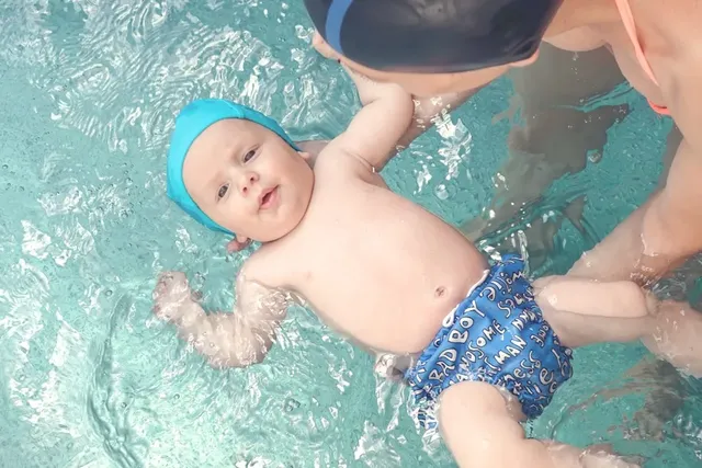 Baby lernt Schwimmen mit Elternunterstützung im Pool