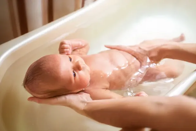 Baby wird in Badewanne gehalten
