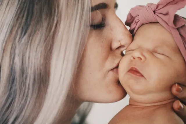Junge Mutter küsst Baby Mädchen