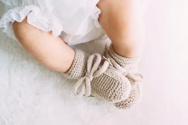 Baby mit Schühchen liegt auf weissem Untergrund