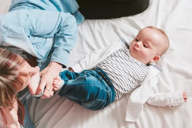 Junge Mutter liegt mit Baby im Bett