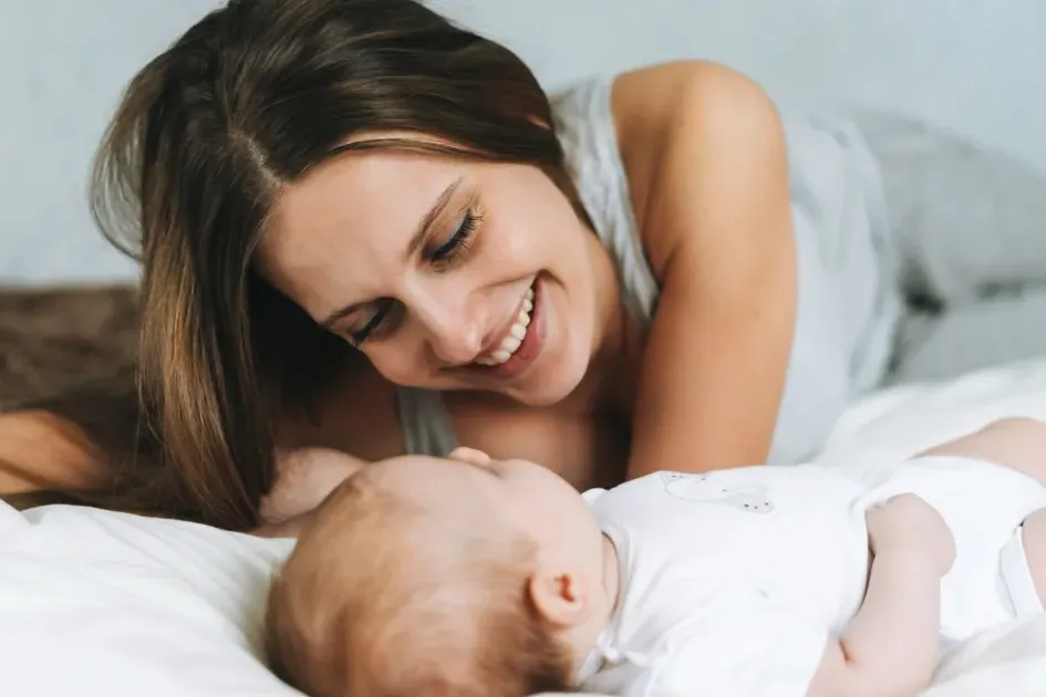 Mutter mit Baby im Bett lachend