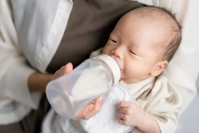 Junge Mutter füttert ihr Baby mit einem Fläschchen
