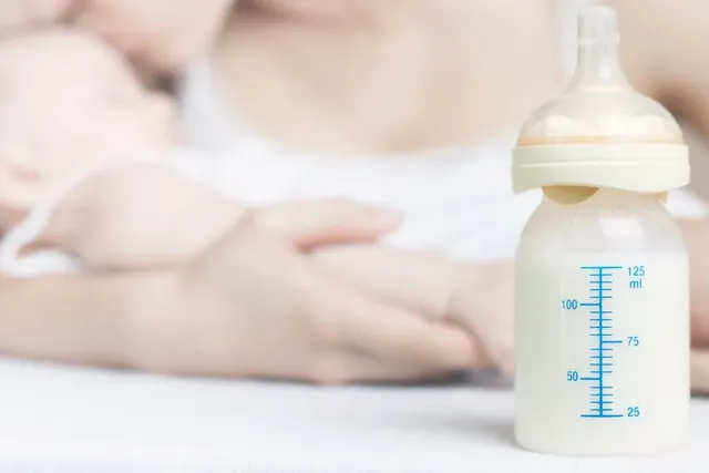 Junge Mutter und ihr Baby mit voller Milchflasche