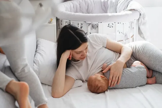 Junge Mutter und ihr Baby liegen im Bett