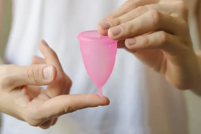 Frau hält Menstruationstasse in den Händen