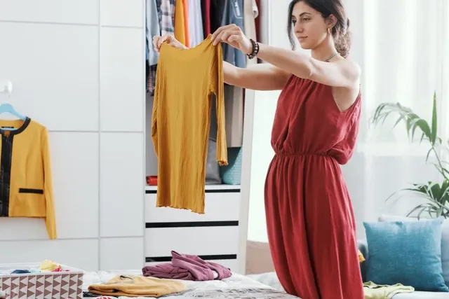 Schwangere Frau sortiert Kleidung für das Babyzimmer.