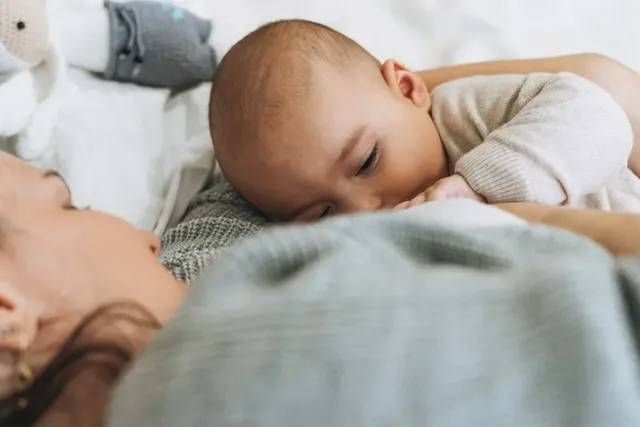 Junge Mutter stillt ihr Baby auf einer Fensterbank