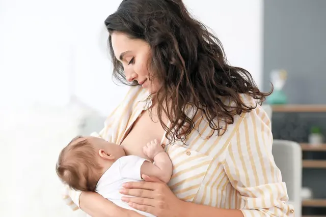Mutter stillt liebevoll ihr Baby zu Hause