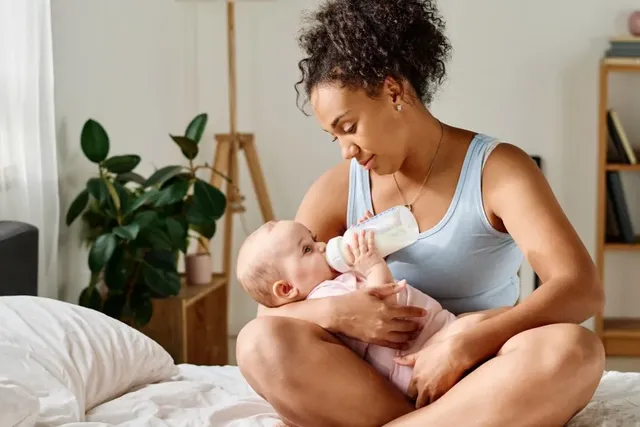 Junge Mutter und ihr Baby mit voller Milchflasche