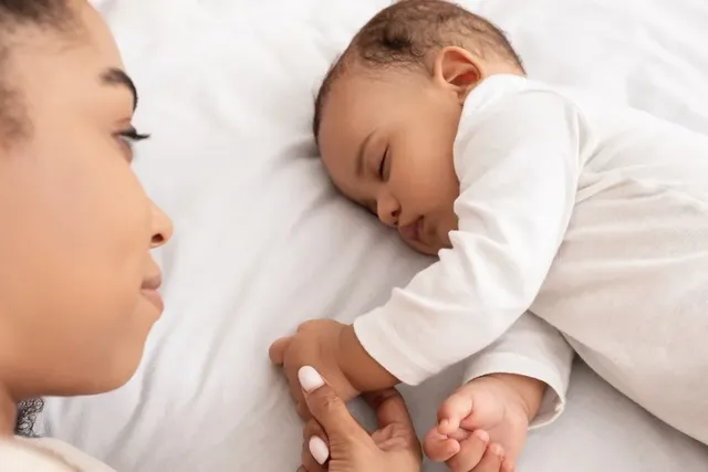 Aufgewachtes Baby liegt im Bett