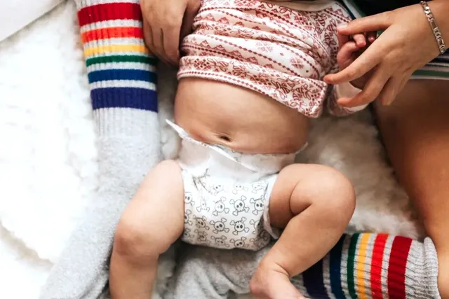 Mutter und Baby in Windeln sitzen im Bett