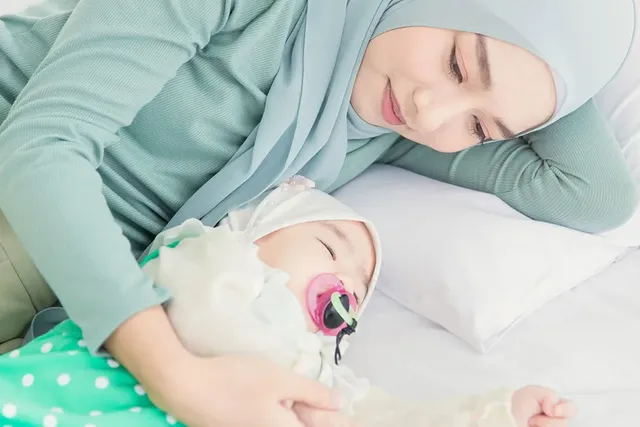 Mutter legt sich liebevoll neben schlafendes Baby mit Schnuller.