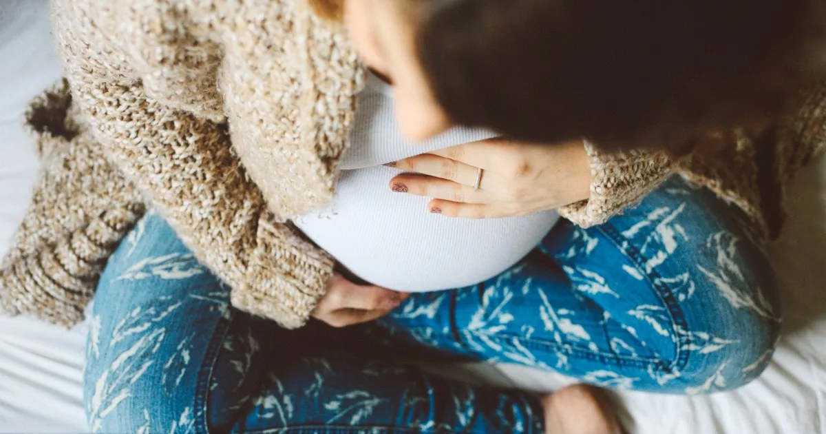 Schwangere Frau hält schützend ihren Babybauch.