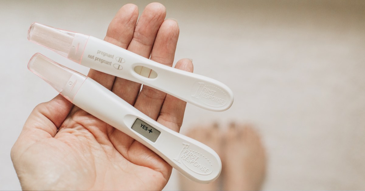 Frau hält positive Schwangerschaftstests