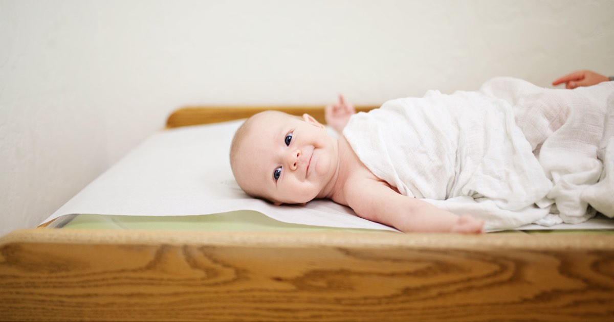 Baby lächelt und liegt auf Wickeltisch