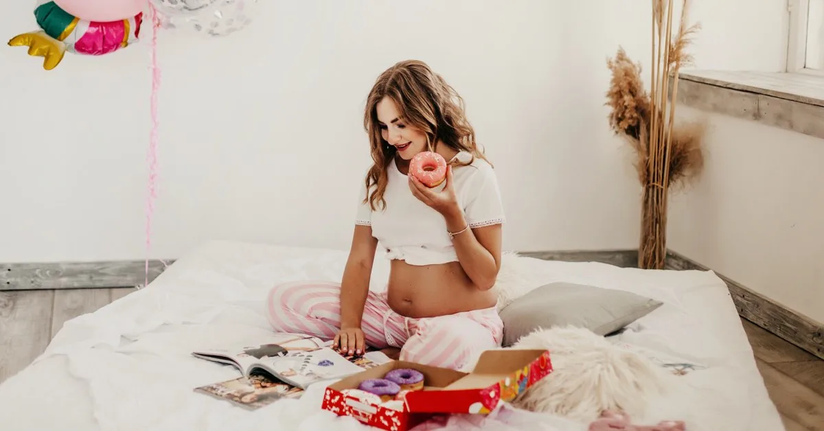 Schwangere Frau isst Donuts im Bett