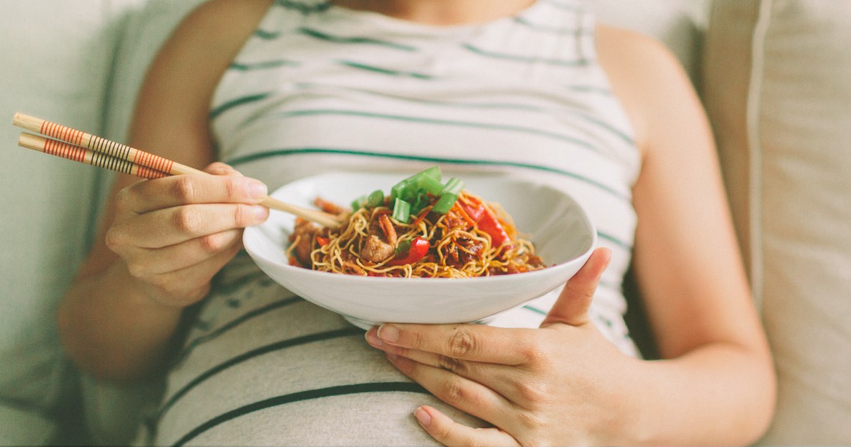 Schwangere Frau mit Heißhunger isst Asia Nudeln