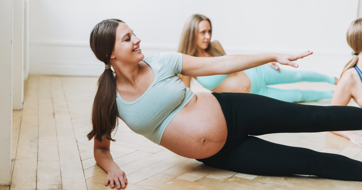 Schwangere Frau in einem Gymnastikraum, Sportgeräte und Bälle im Hintergrund