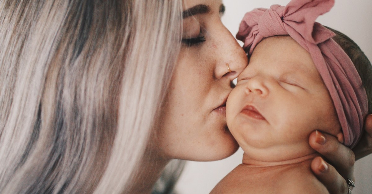 Junge Mutter küsst Baby Mädchen