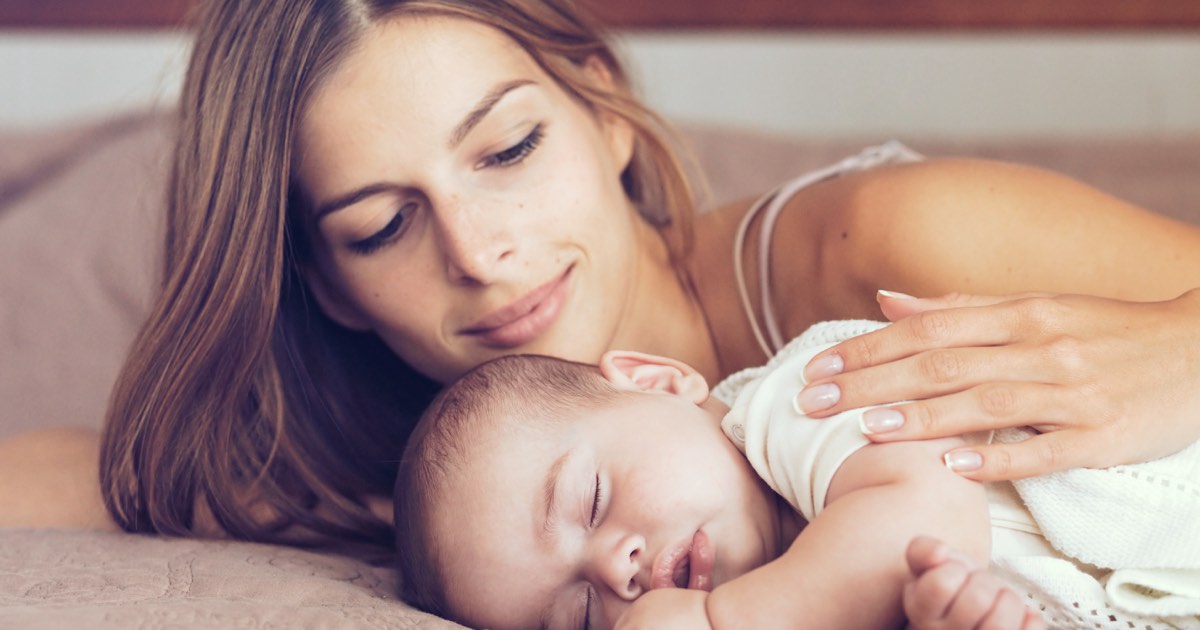 Junge Mutter und ihr Neugeborenes im Bett