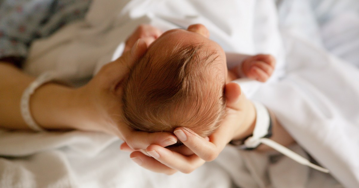 Mutter hält Neugeborenes nach Geburt im Spital