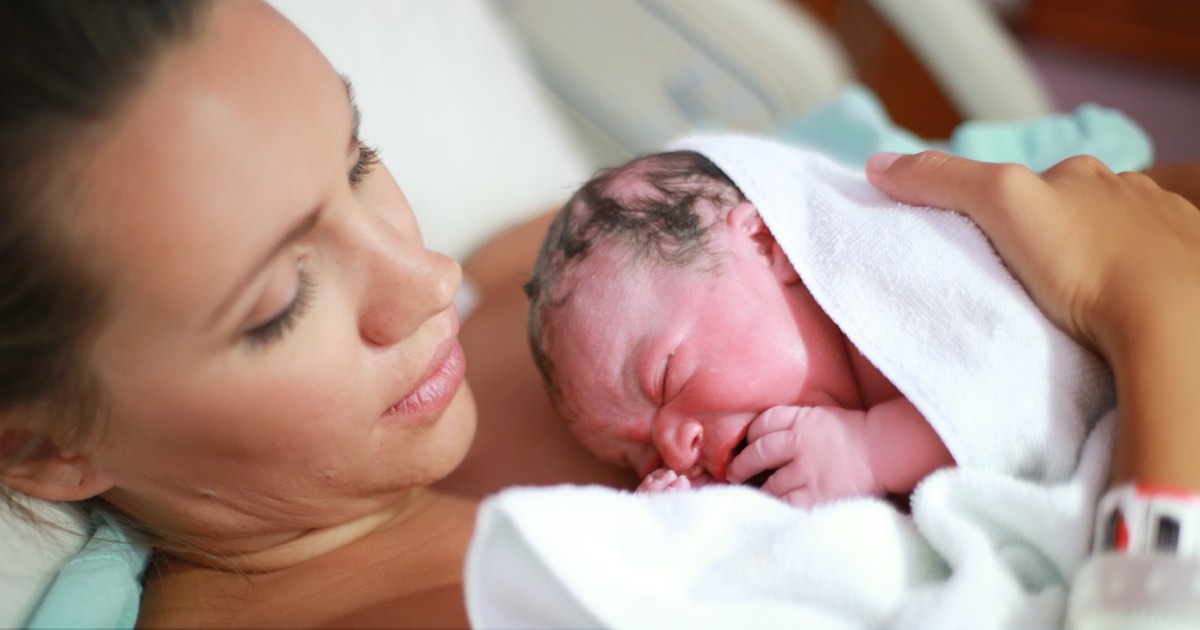 Mutter hält Neugeborenes nach Geburt im Spital