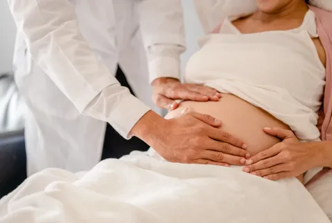 Schwangere hält Stetoskop an Bauch