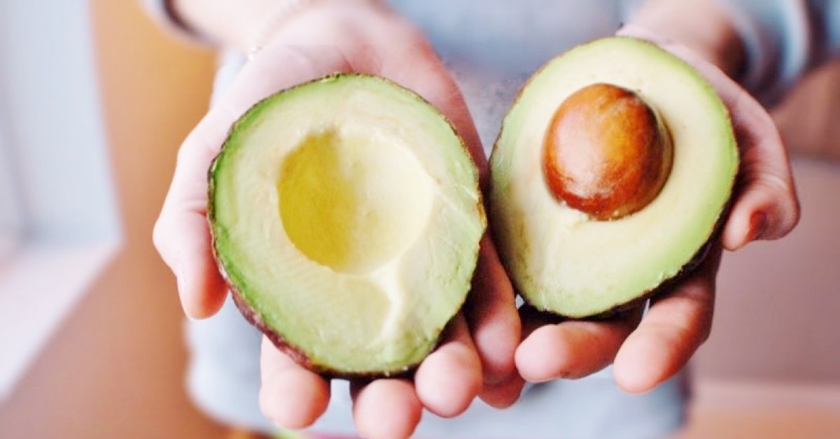 Frau hält aufgeschnittene Avocado