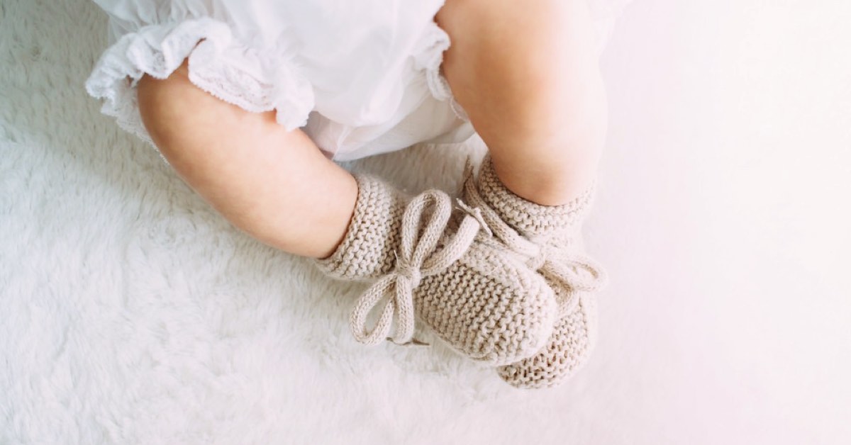 Baby mit Schühchen liegt auf weissem Untergrund