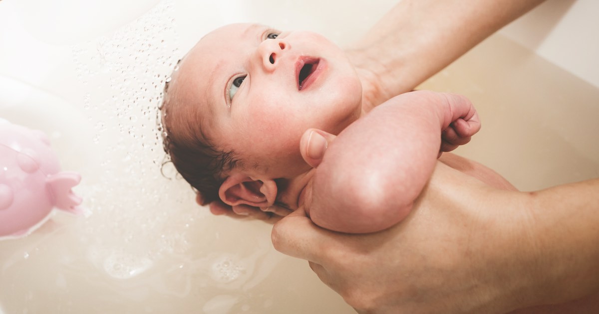 Baby wird in Badewanne gehalten