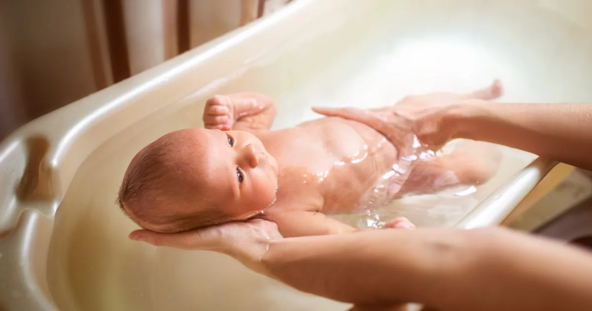 Baby wird in Badewanne gehalten