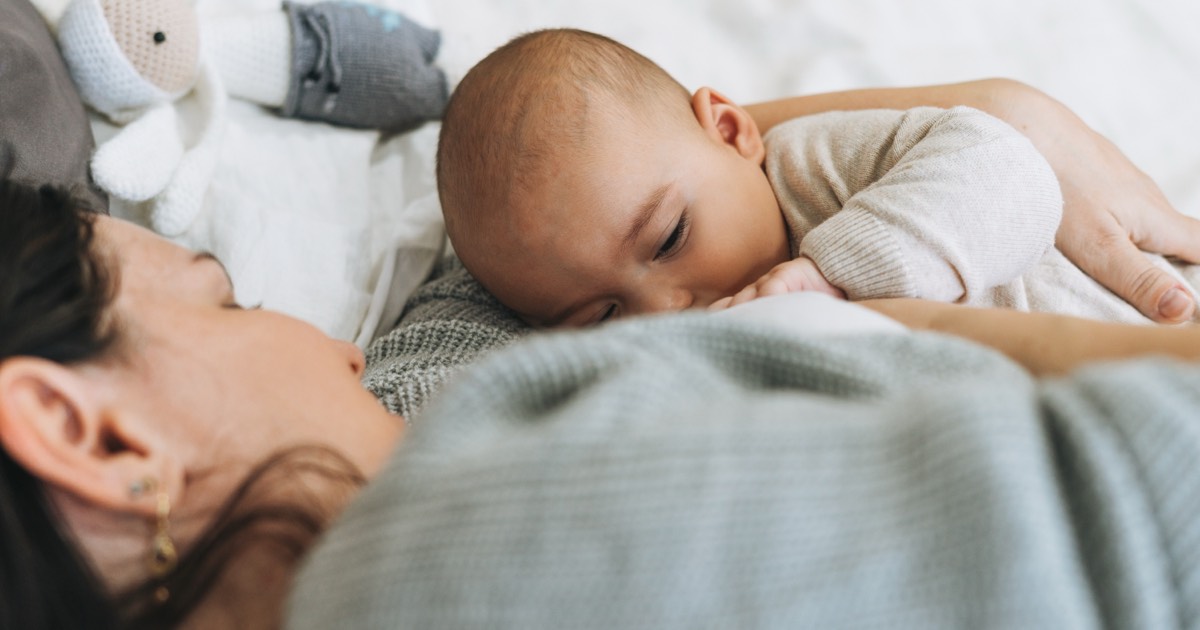 Junge Mutter stillt ihr Baby auf einer Fensterbank