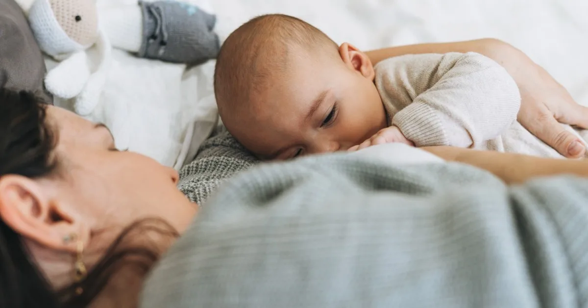 Junge Mutter stillt ihr Baby auf einer Fensterbank