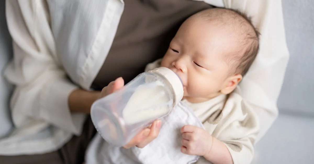 Junge Mutter füttert ihr Baby mit einem Fläschchen