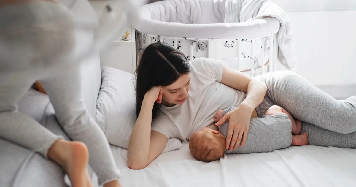 Junge Mutter und ihr Baby liegen im Bett