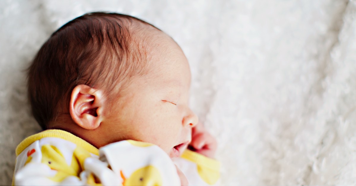 Familie im Bett mit dem Baby in der Mitte