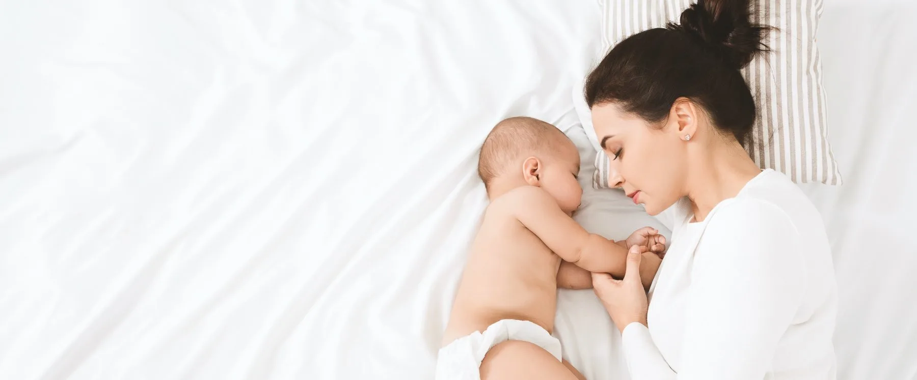 Mutter und Baby schlafen friedlich nebeneinander im Bett.