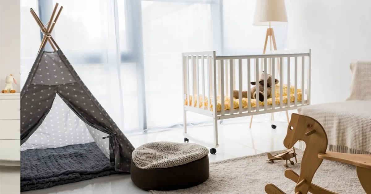 Helles Babyzimmer mit Kinderbett, Spielzelt und Holzschaukelpferd.