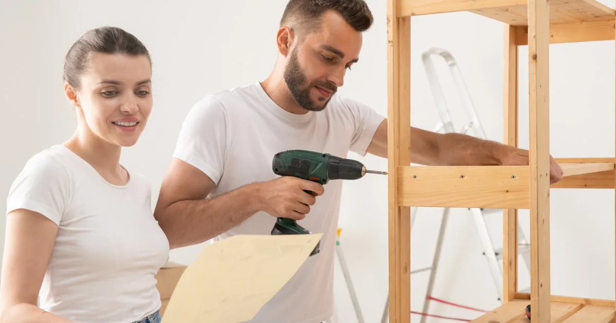 Junges Paar baut gemeinsam Möbel für das Kinderzimmer zusammen.