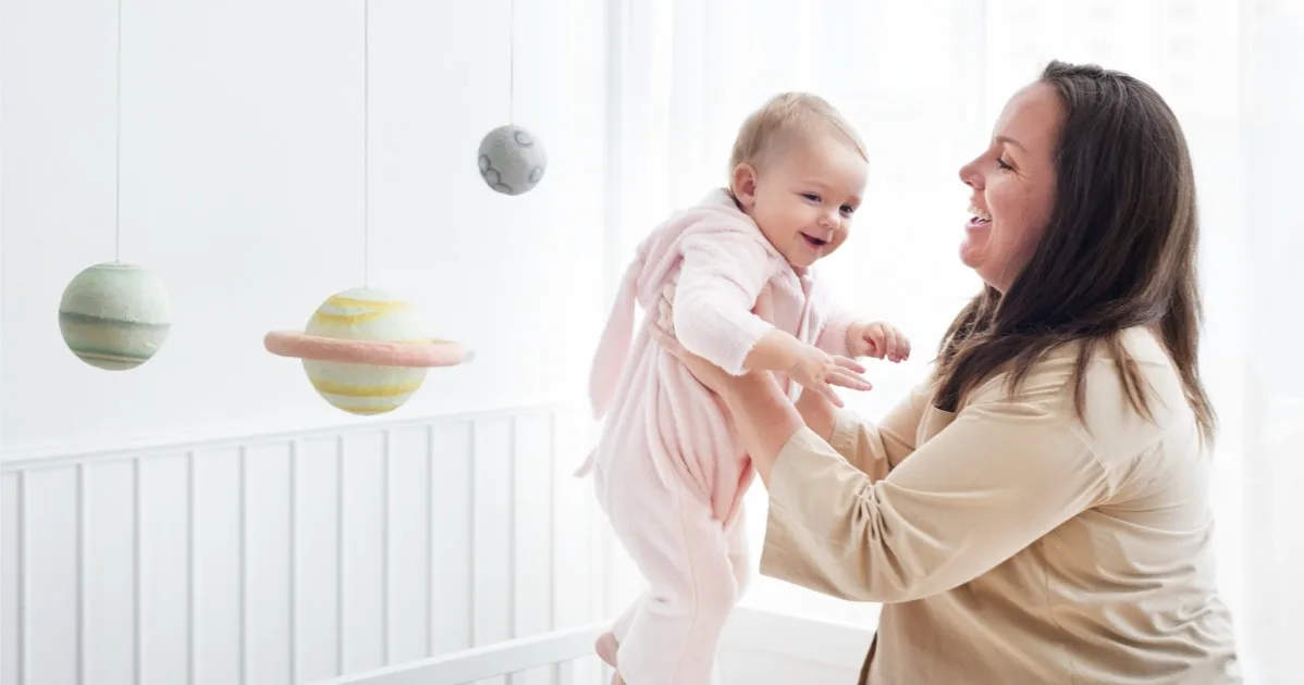 Mutter spielt fröhlich mit ihrem Baby im Kinderzimmer.