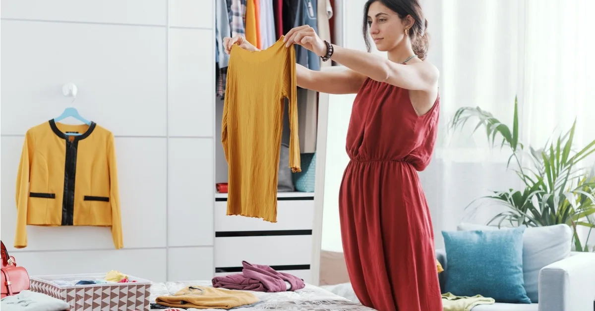 Schwangere Frau sortiert Kleidung für das Babyzimmer.
