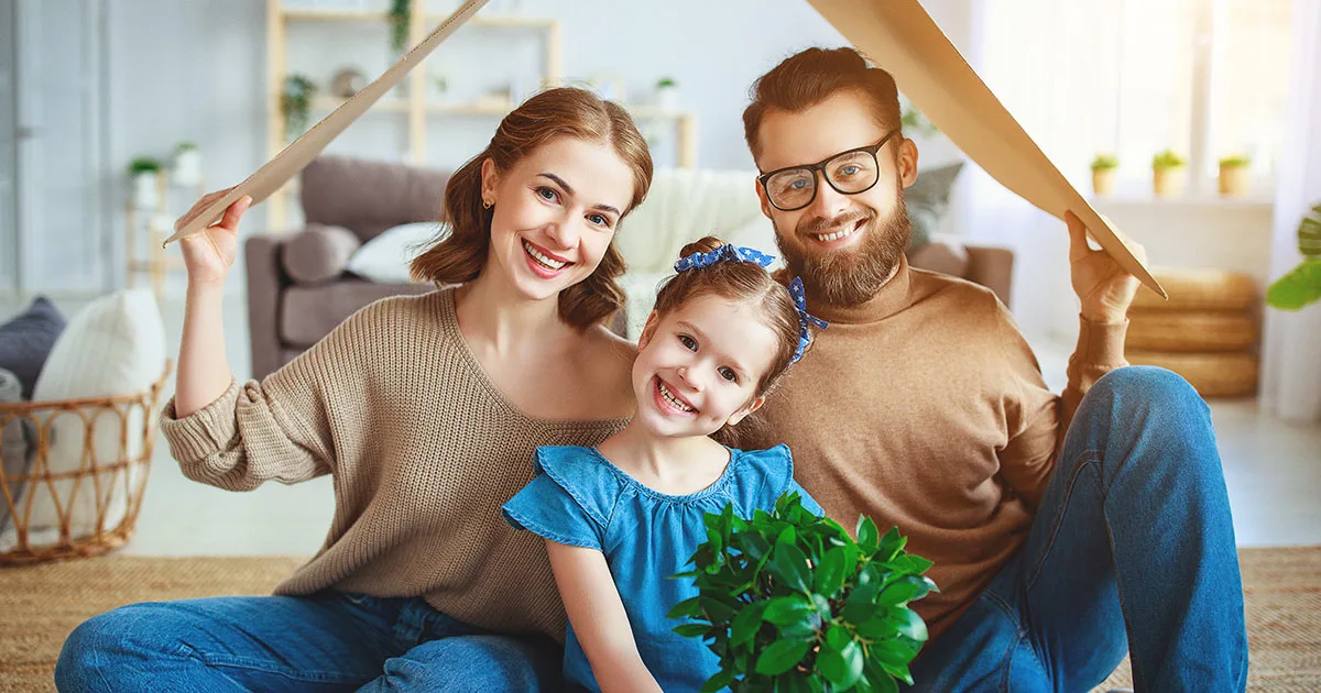 Glückliche Familie mit Kind unter Pappdach im Wohnzimmer