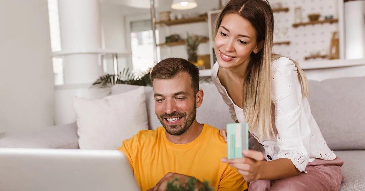 Junges Paar plant Familienausgaben mit Laptop und Kreditkarte zu Hause.