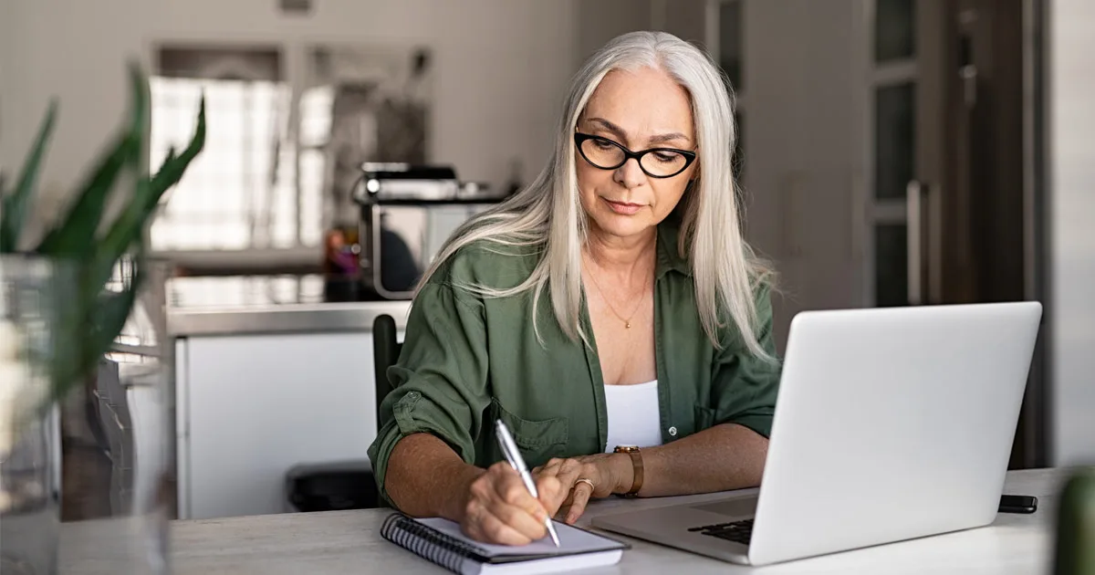 Reife Frau arbeitet am Laptop und macht Notizen, Familienplanung und Vorbereitung auf Schwangerschaft.