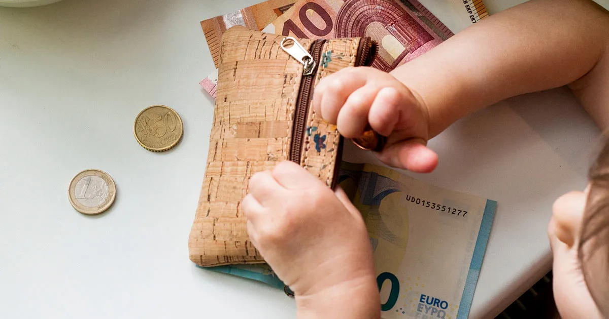 Baby spielt mit Geld und Geldbörse – Familie und Finanzen im Blick