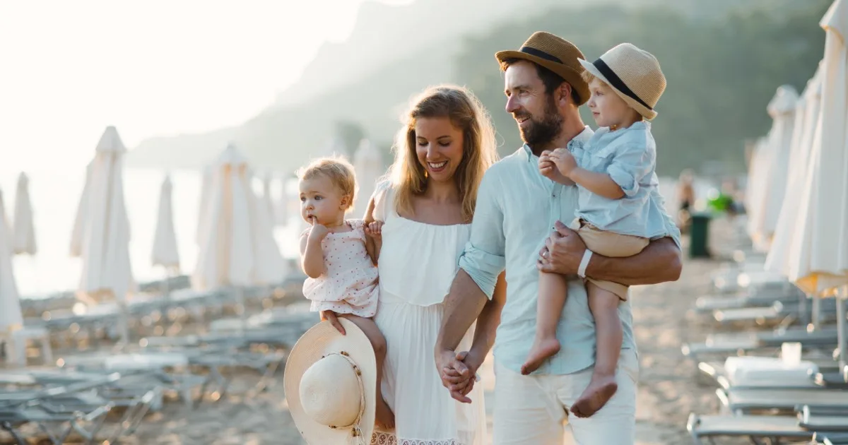 Familie mit Kleinkindern spaziert glücklich am Strand bei Sonnenuntergang