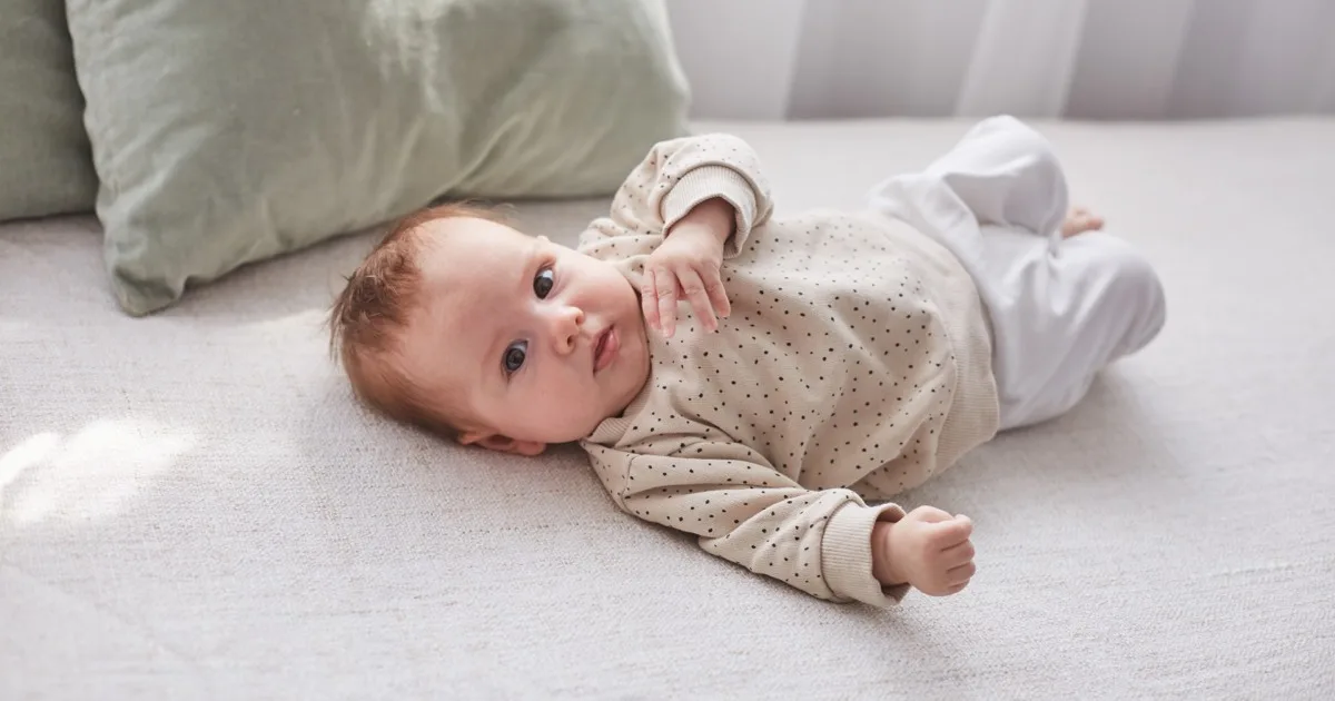 Baby liegt entspannt auf dem Rücken auf dem Bett