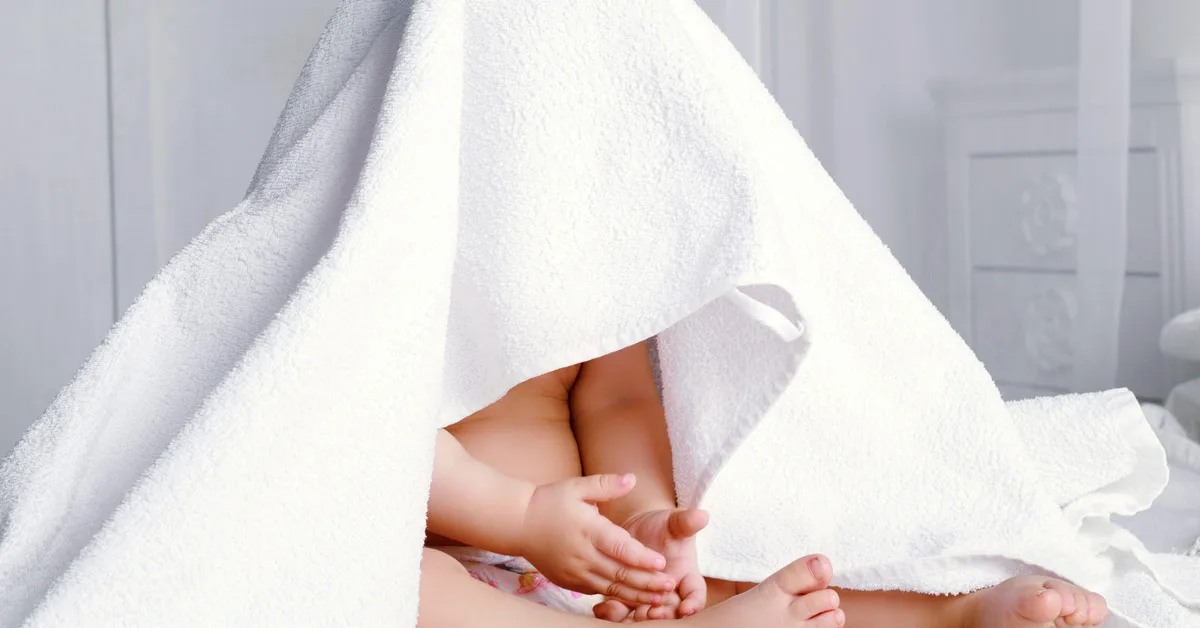 Baby mit einem Badetuch über dem Kopf